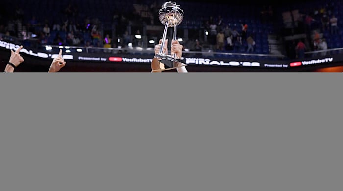 Aces forward A’ja Wilson holds up the WNBA championship trophy with her teammates around her.